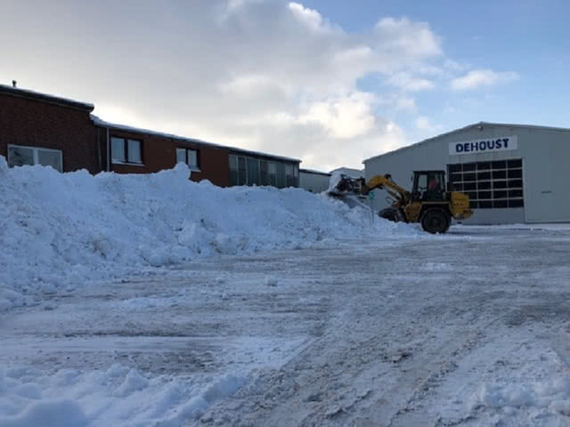 Der Schnee wird vor einer Lagerhalle geräumt.